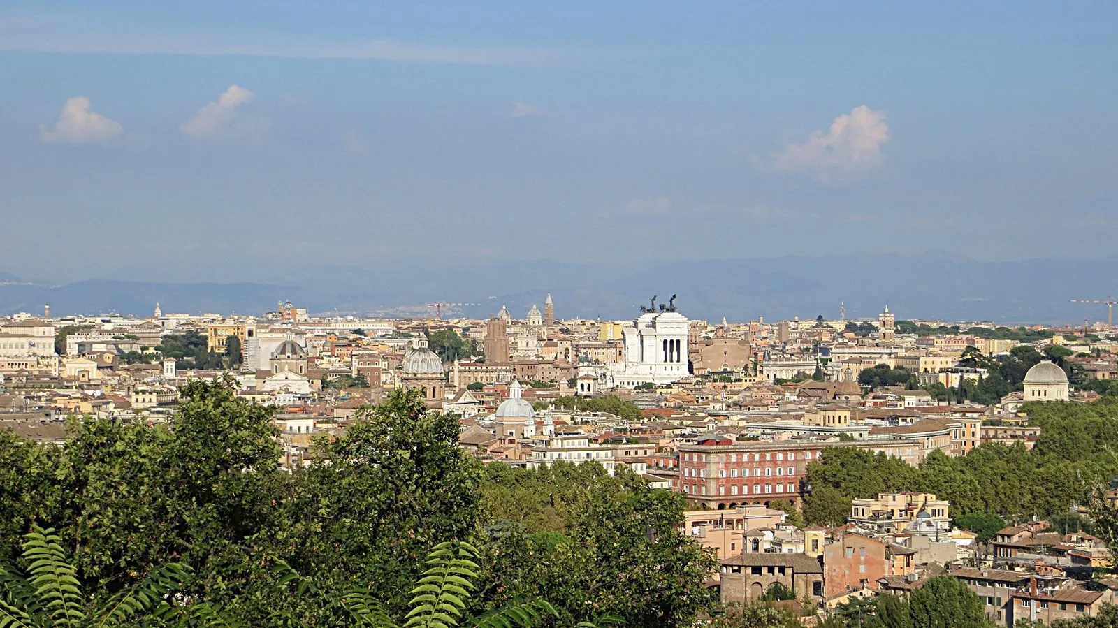 Panorama dei tetti e delle cupole di Roma con il Vittoriano al centro e i colli sullo sfondo
